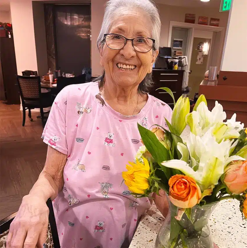Resident smiling with flowers in a common area