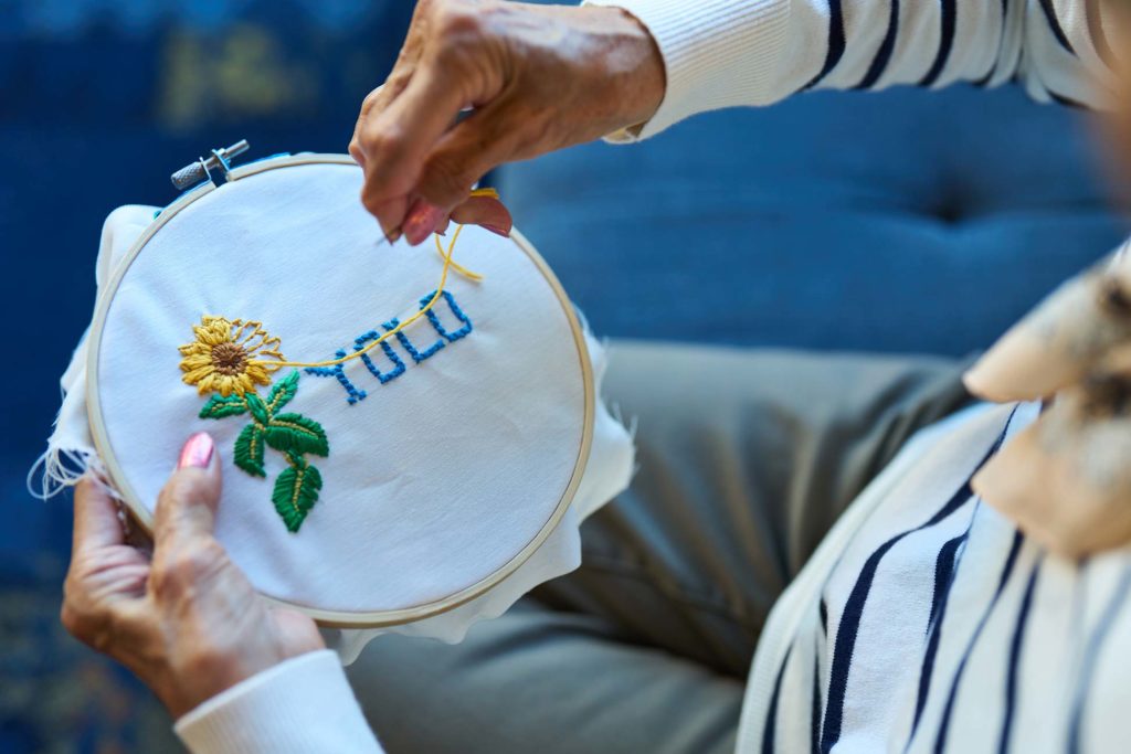 Resident embroidering a colorful 'YOLO' design