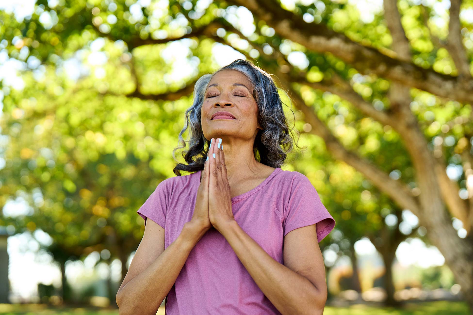 A woman with closed eyes, meditating in a garden