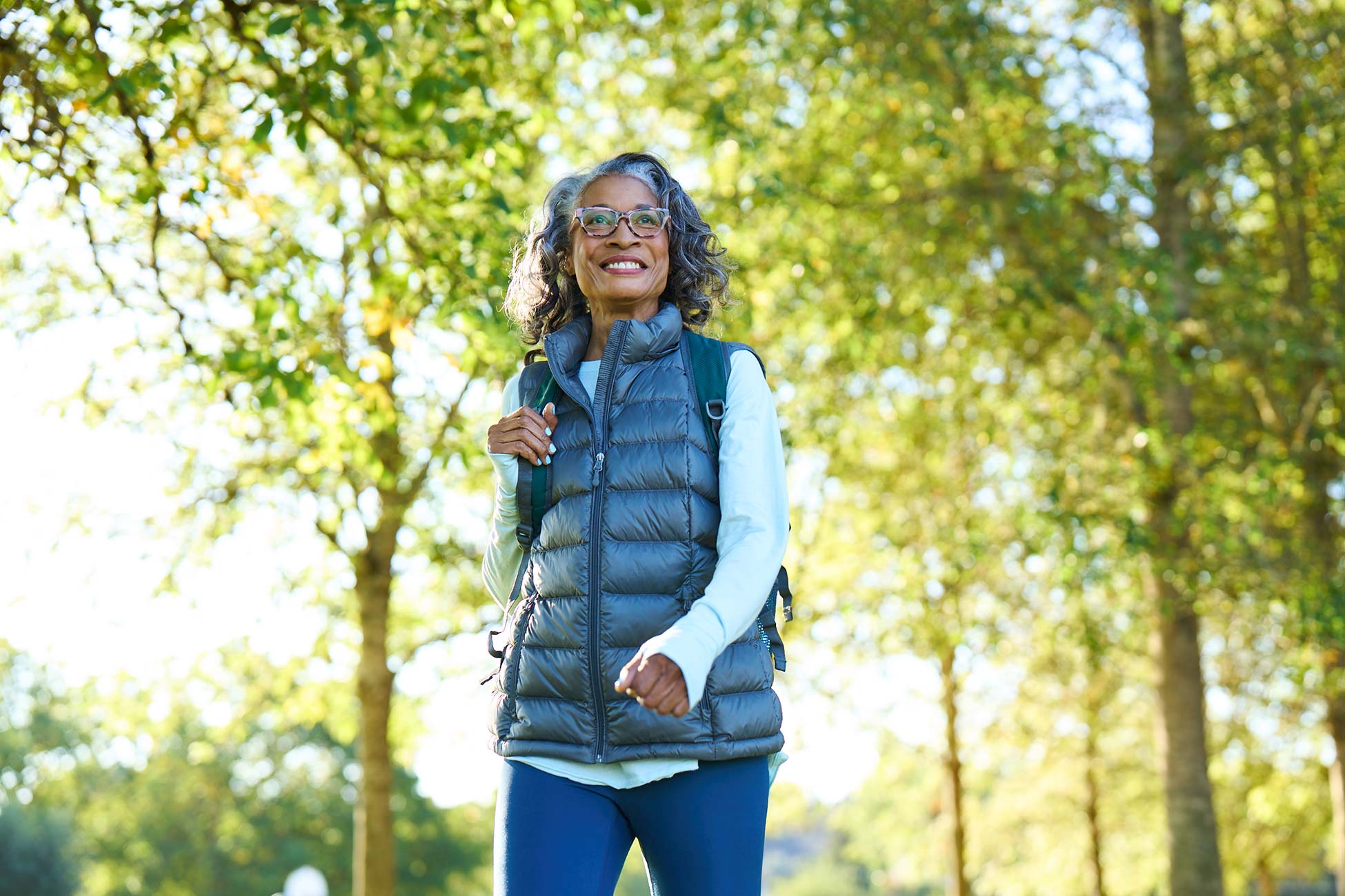 A woman walking in a park surrounded by trees
