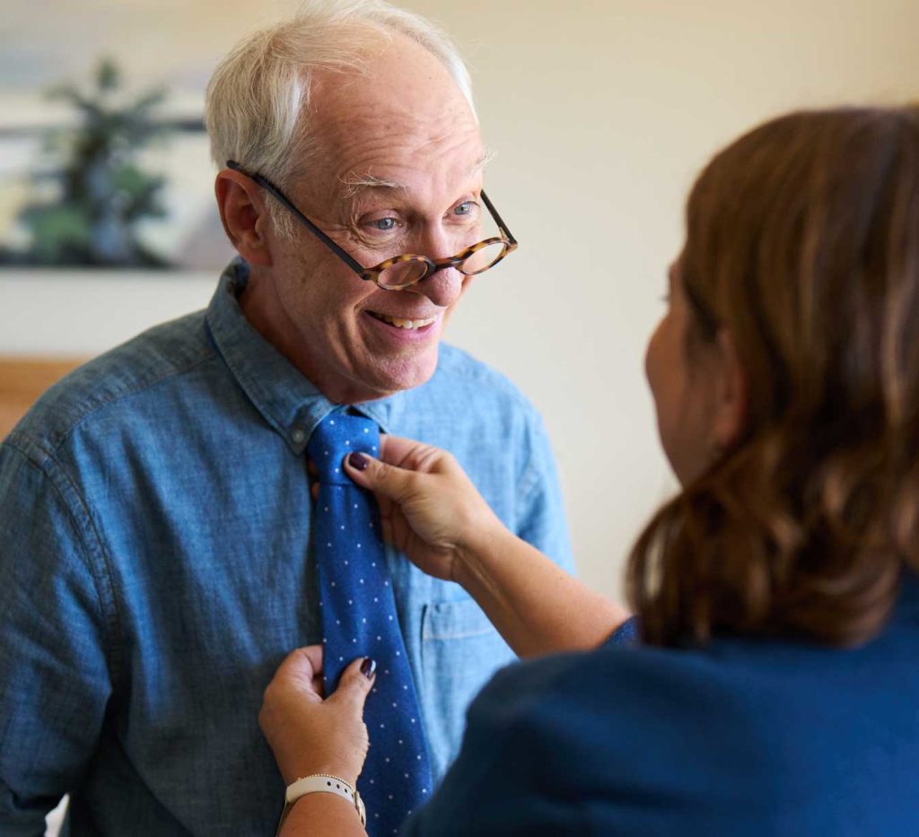 A resident smiling while adjusting a tie.