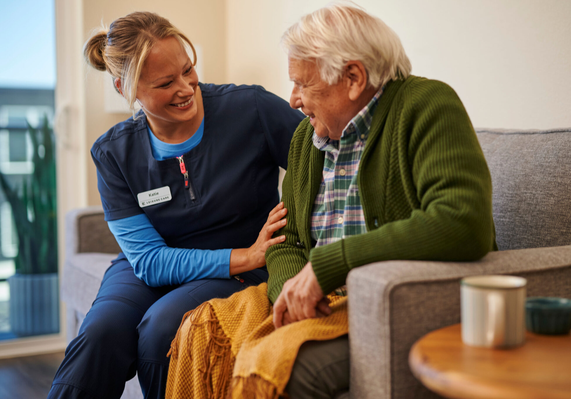 A caregiver smiling with a senior resident in a cozy setting