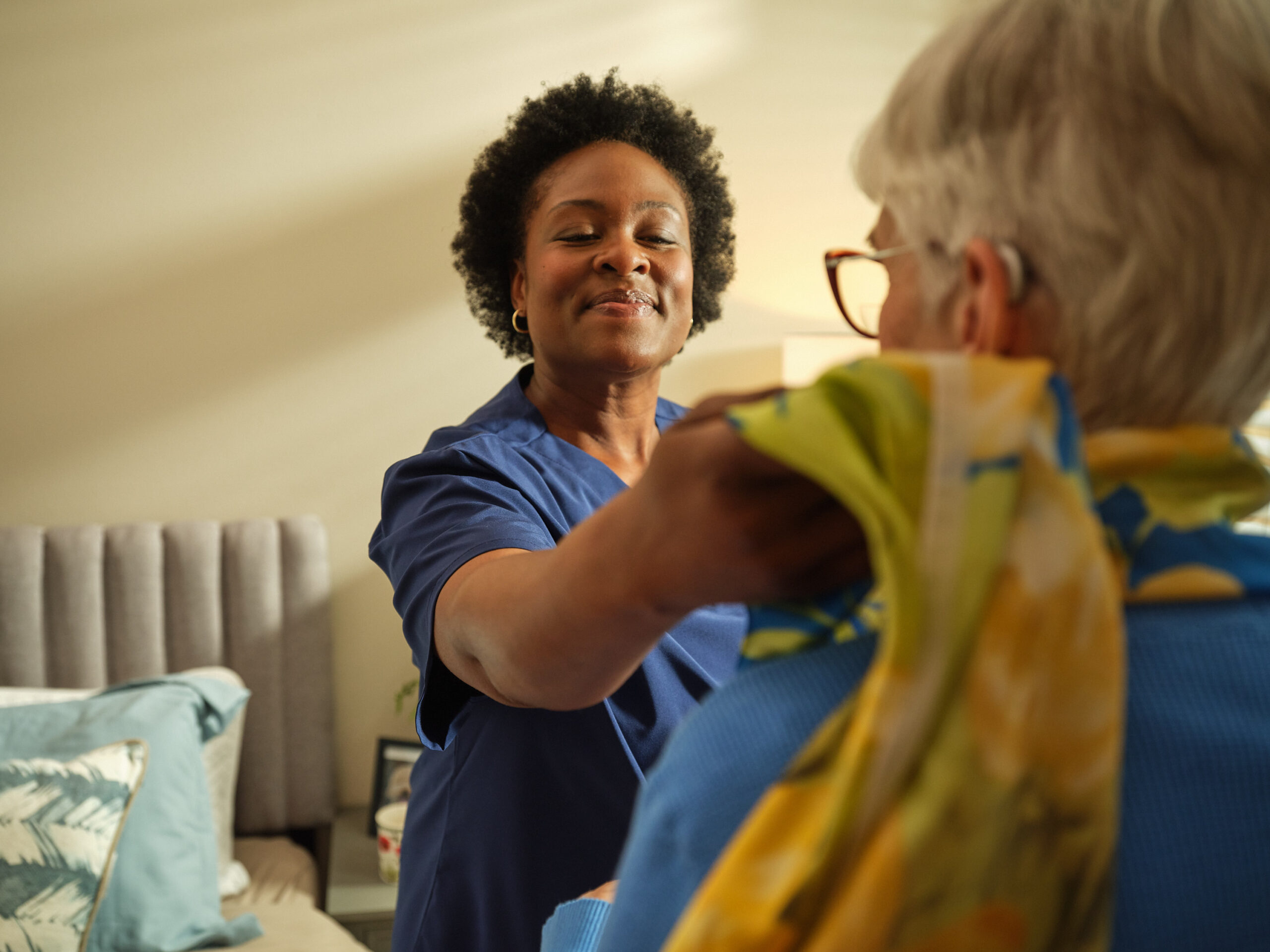 A caregiver assisting a senior resident in a room