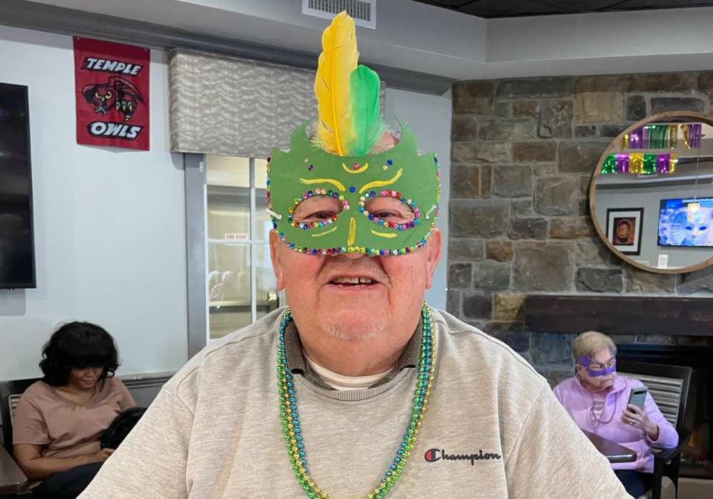Resident celebrating in a colorful mask during an activity