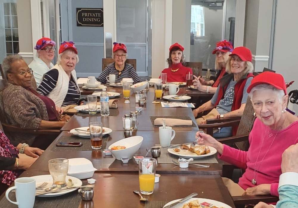 Residents enjoying breakfast and wearing red hats