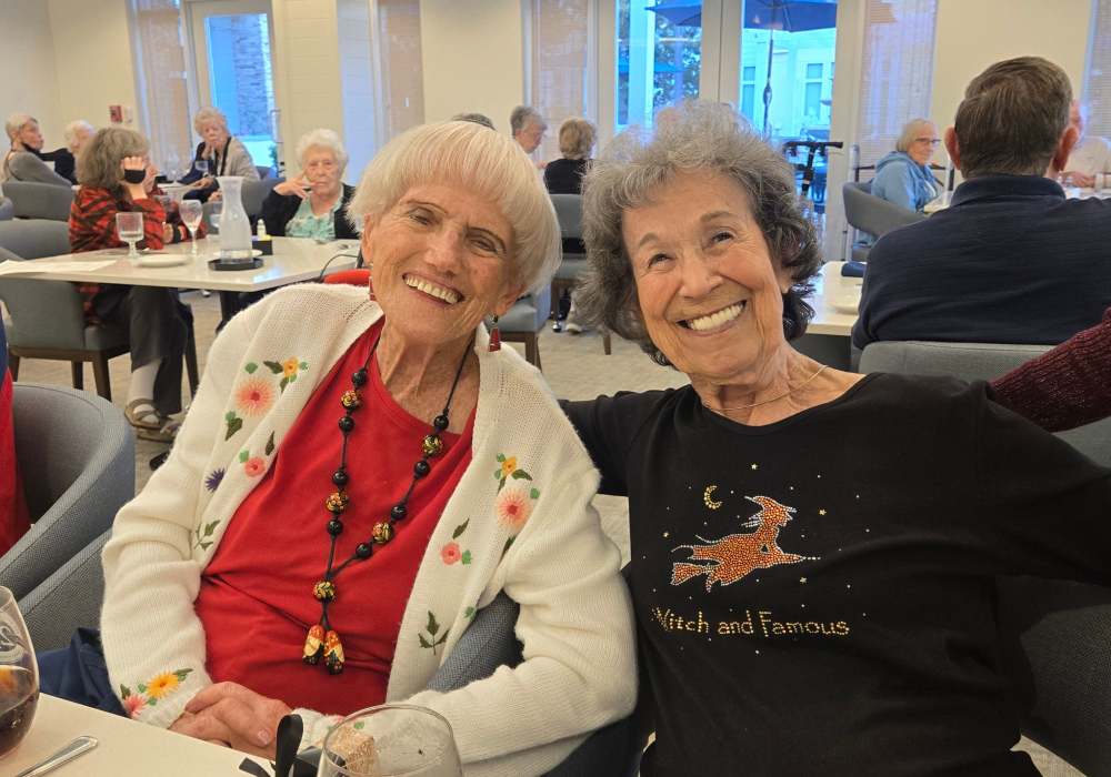 Two senior women smiling together at a dining table