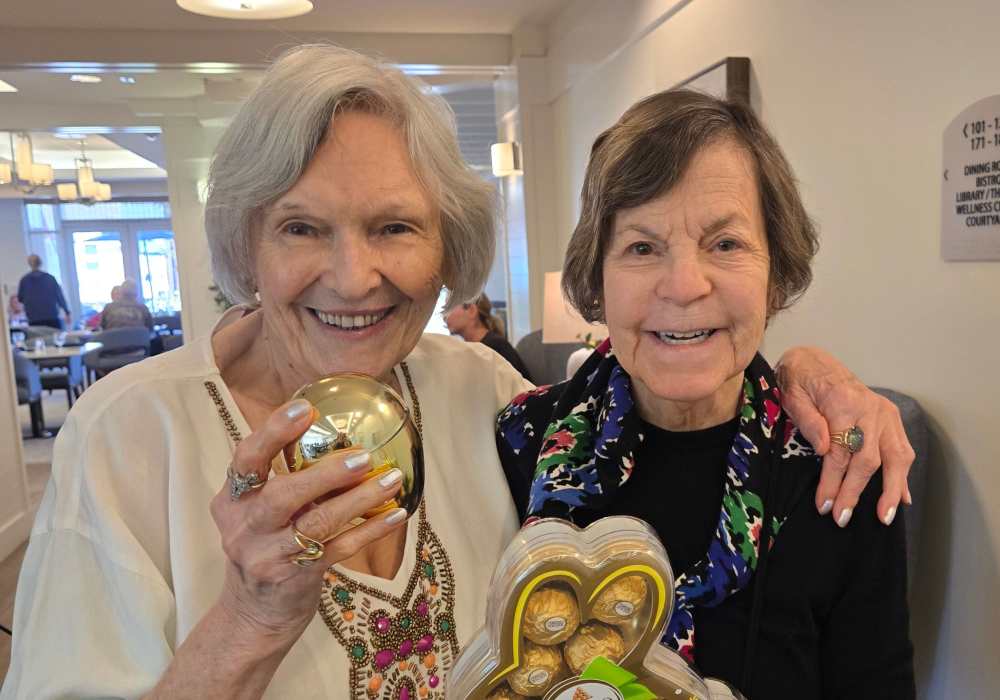 Two smiling residents holding gifts in a common area