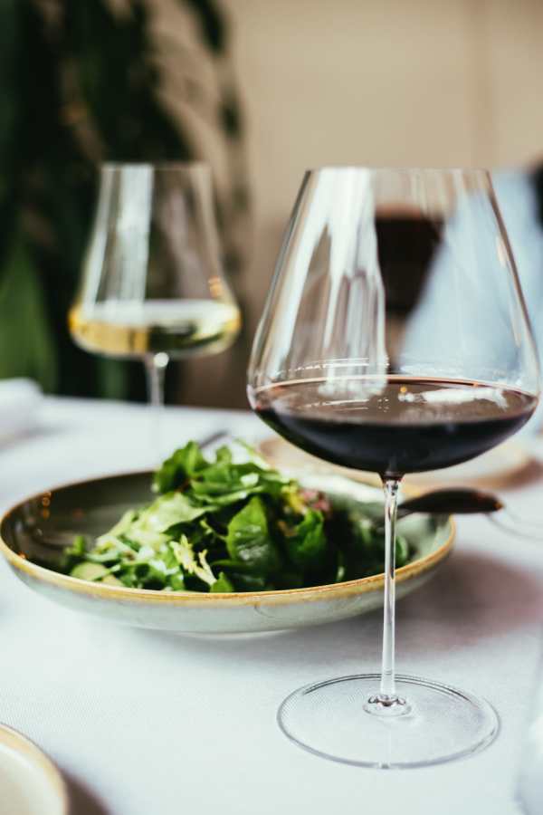 A close-up of wine glasses and a salad plate