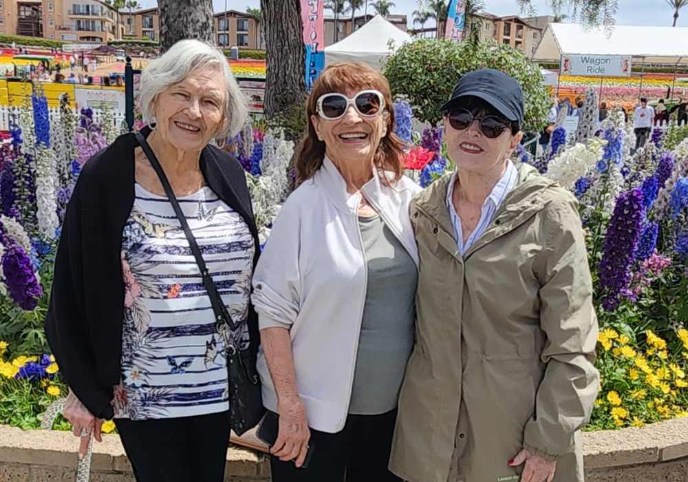 Three women smiling in a flower garden