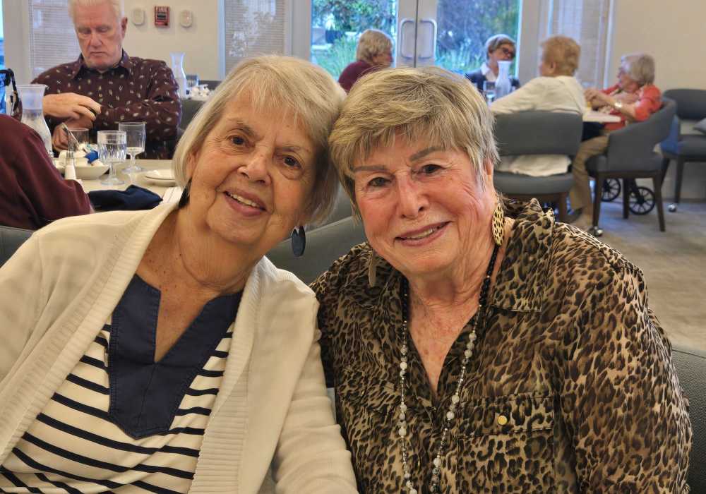 Two smiling residents sitting together in a common area