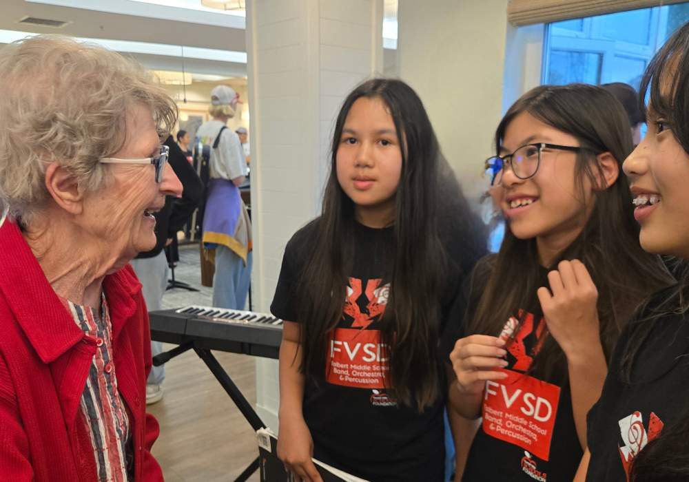 An elderly resident engaging with youth performers