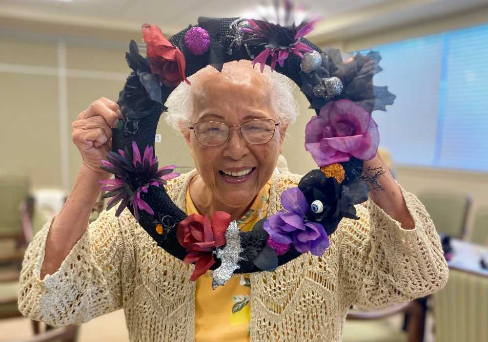Smiling resident holding a decorative wreath in the activity room