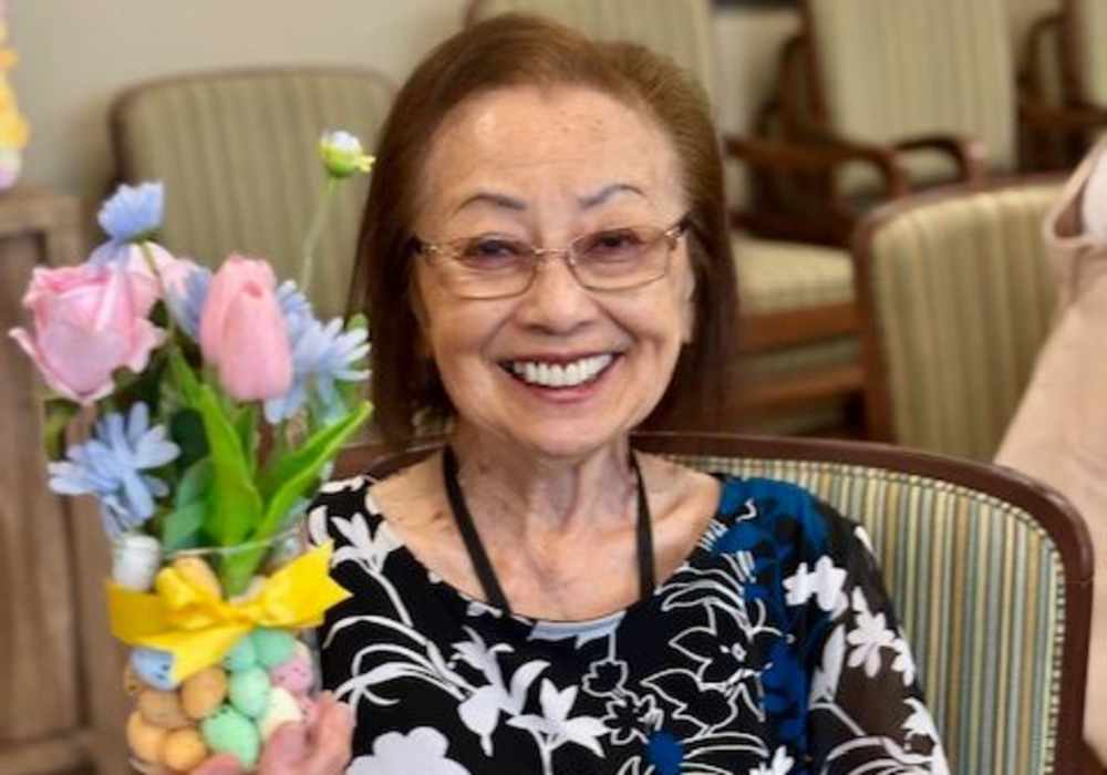 A smiling resident holding a bouquet of flowers in a common area