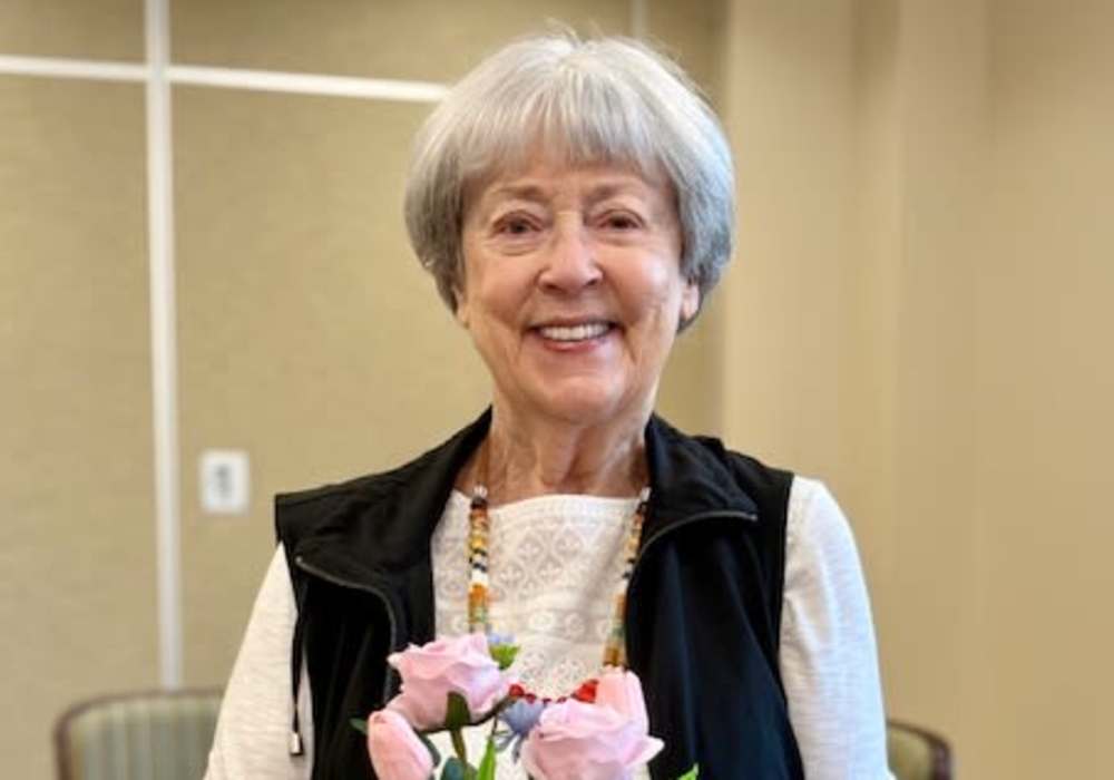 Resident smiling with flowers in a common area