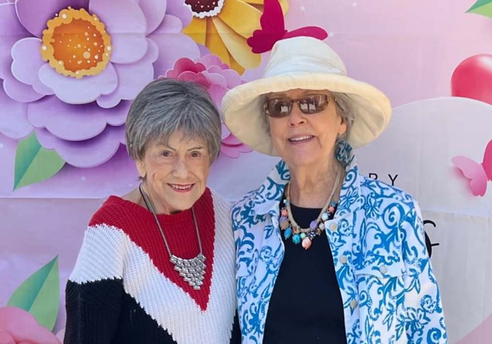 Two residents posing together in front of a floral backdrop