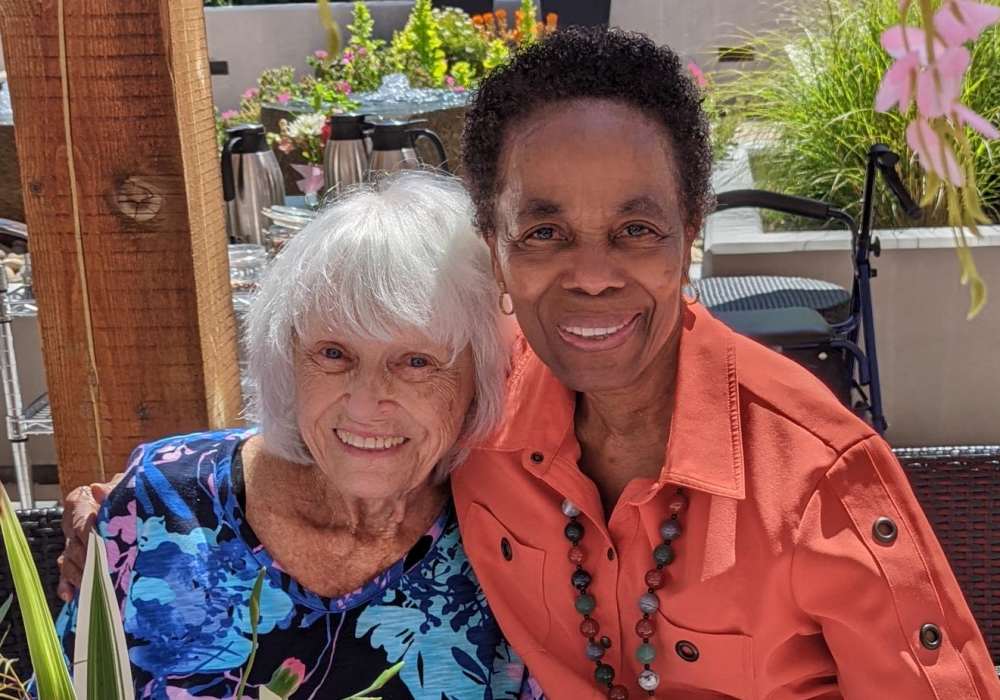 Two residents smiling together in a garden setting