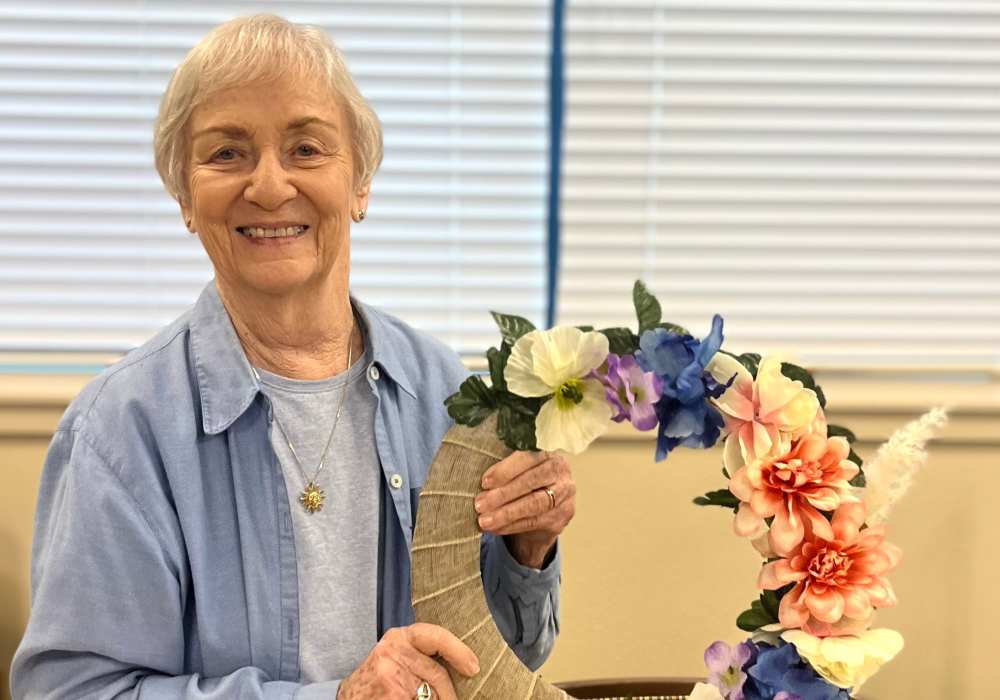 Resident smiling while holding a floral arrangement.