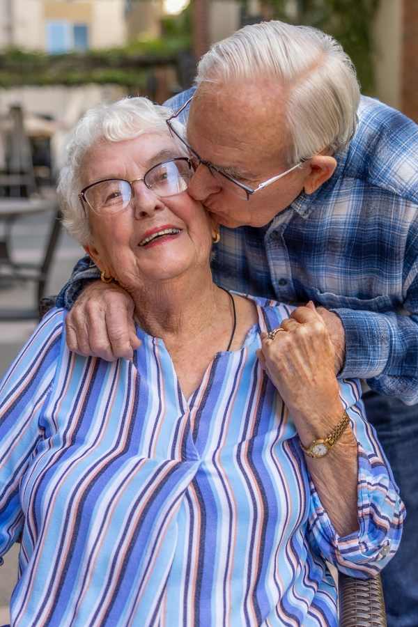 A smiling elderly woman and man in an outdoor setting