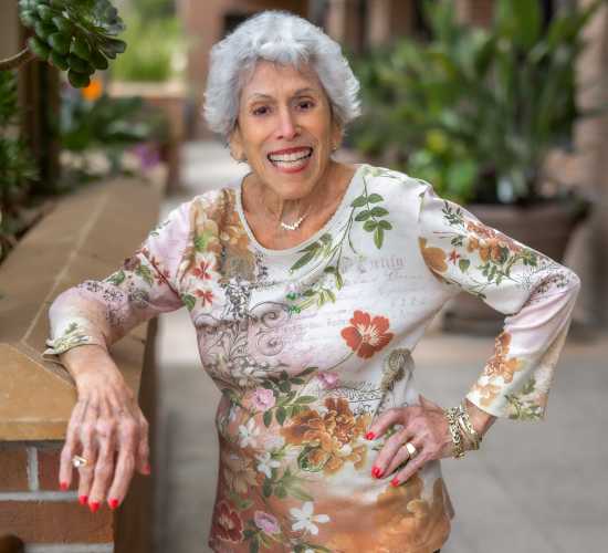 Senior woman smiling outside, dressed in floral attire