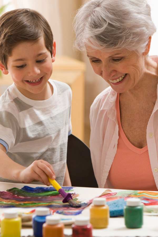 A senior woman and a boy painting together