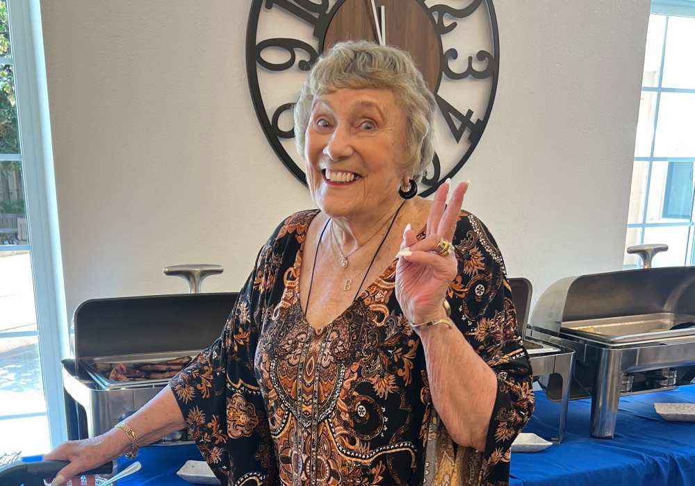 A smiling resident in the dining area showing a peace sign