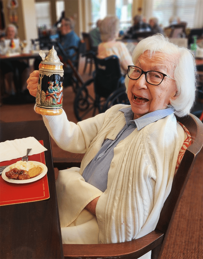 Resident enjoying a meal and smiling at the dining room