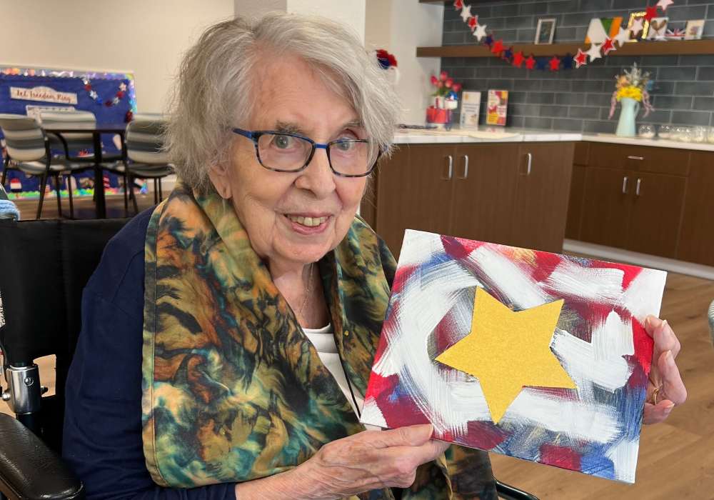 Resident showing artwork in an activity room