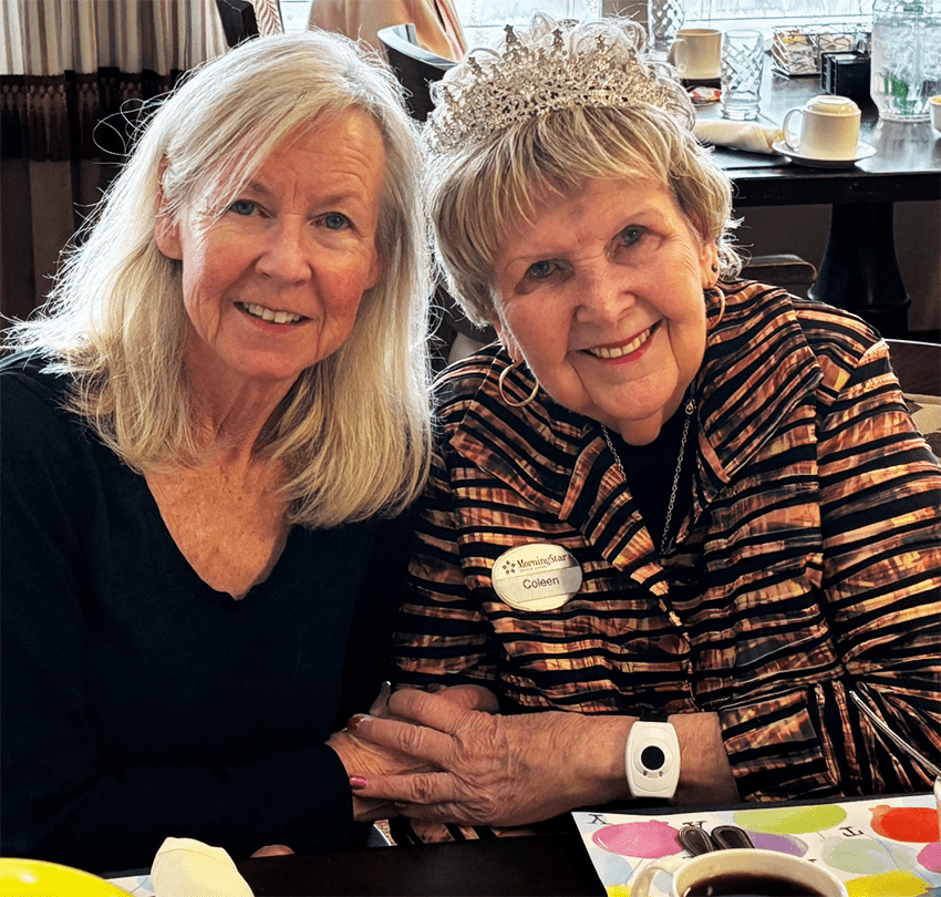 A woman with a tiara and staff member smiling together