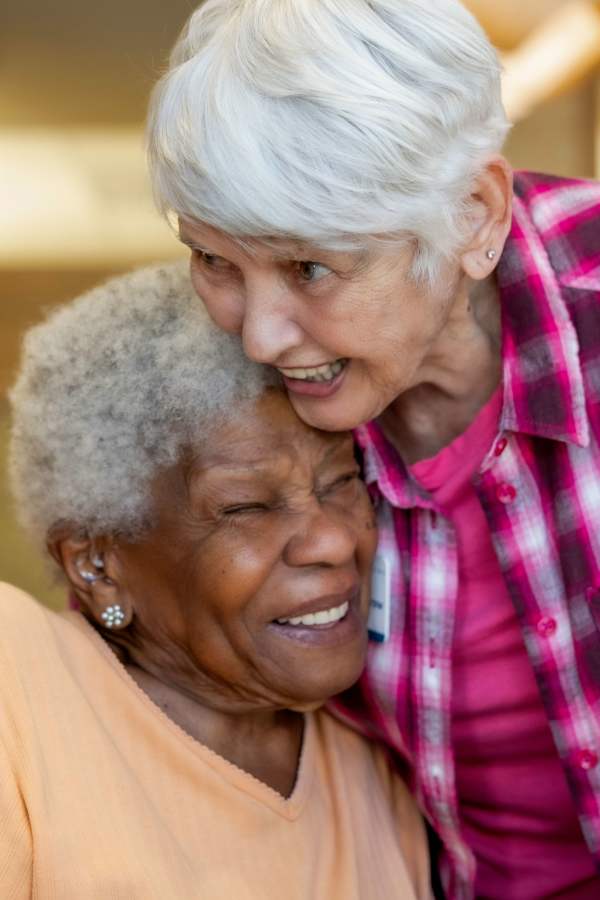 Two smiling residents embracing each other