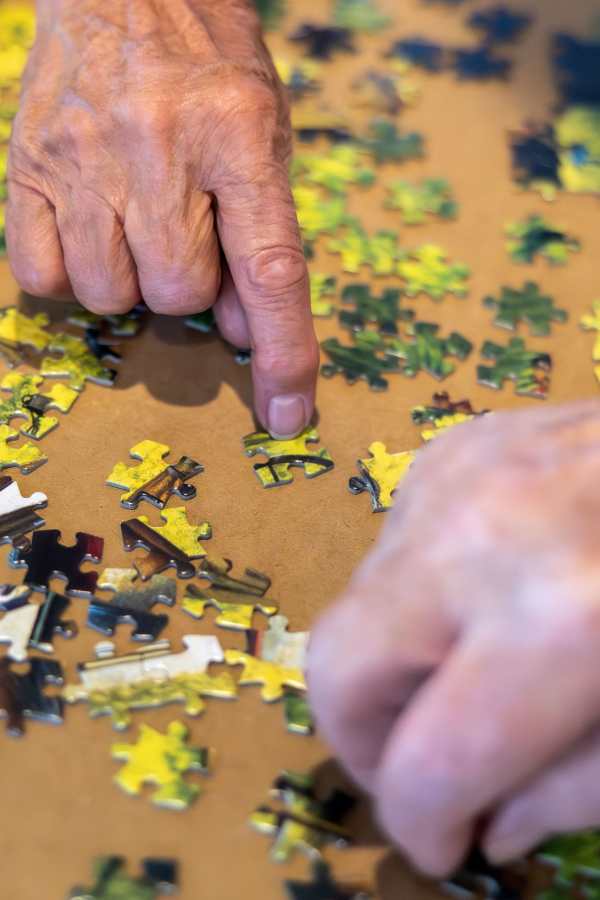 Hands assembling a jigsaw puzzle with colorful pieces