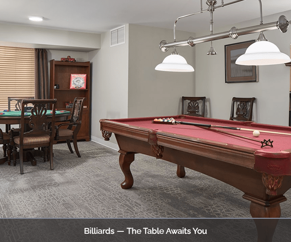A billiards room with a pool table and chairs