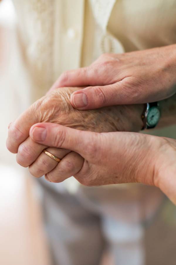 Hands of a caregiver holding a senior's hand