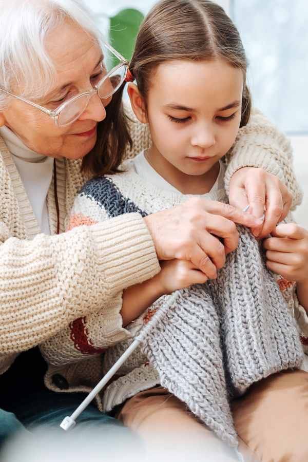 Elderly woman teaching a young girl to knit