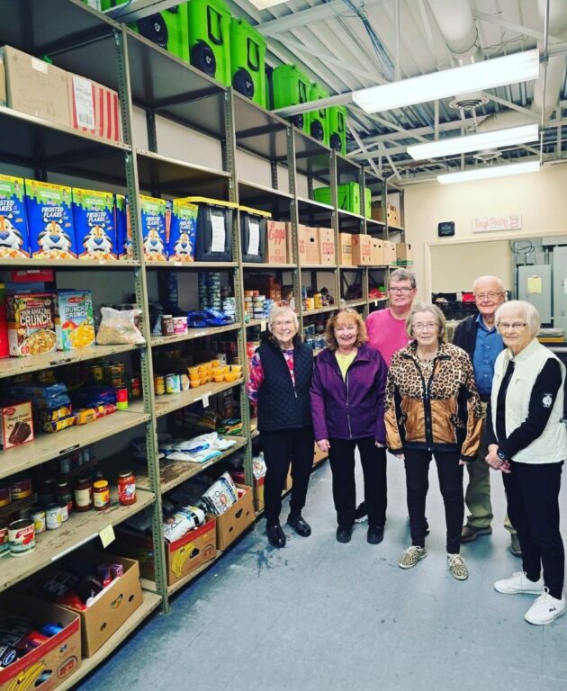 Residents in a food pantry area with shelves of food items