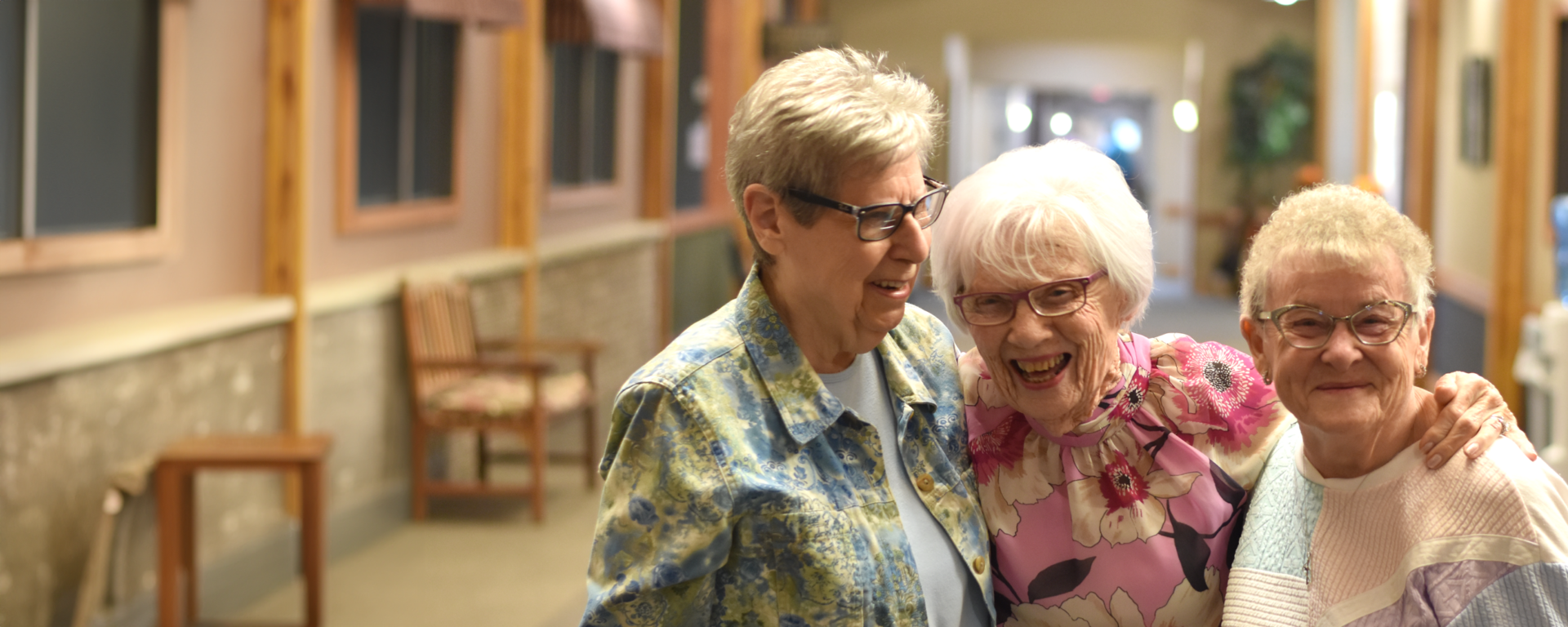 Three residents sharing a joyful moment in a hallway