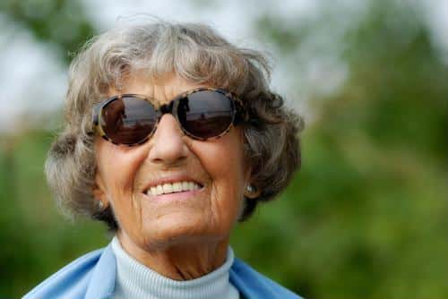 Elderly woman smiling outdoors in sunglasses