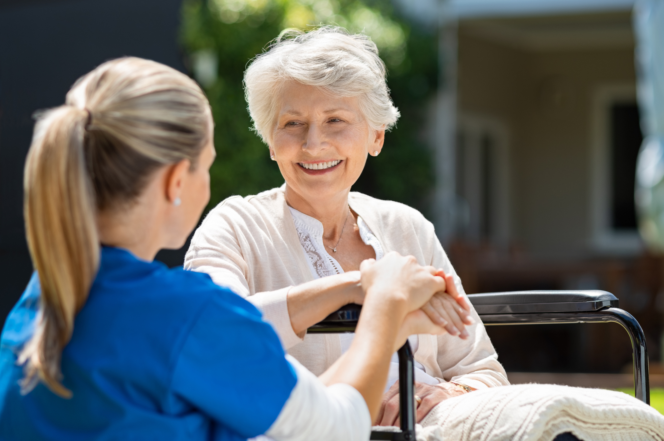 A caregiver holding hands with a smiling resident