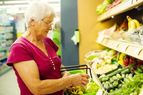 An elderly woman shopping for groceries in a market.