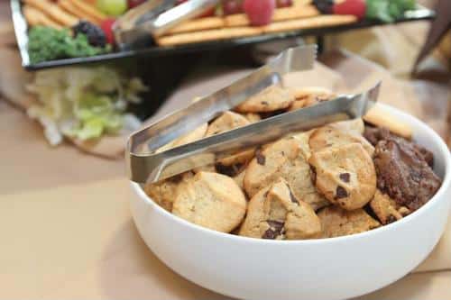 A bowl of assorted cookies with tongs