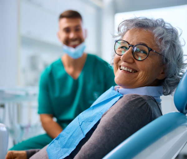 A smiling resident in a dental chair with staff