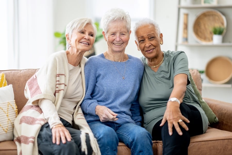Three smiling women sitting together on a couch