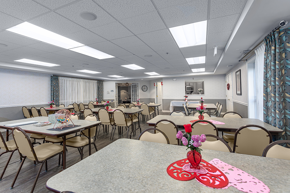 Interior view of a bright common area with tables and flowers