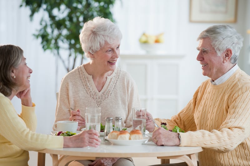 Residents enjoying a meal and conversation in a dining area