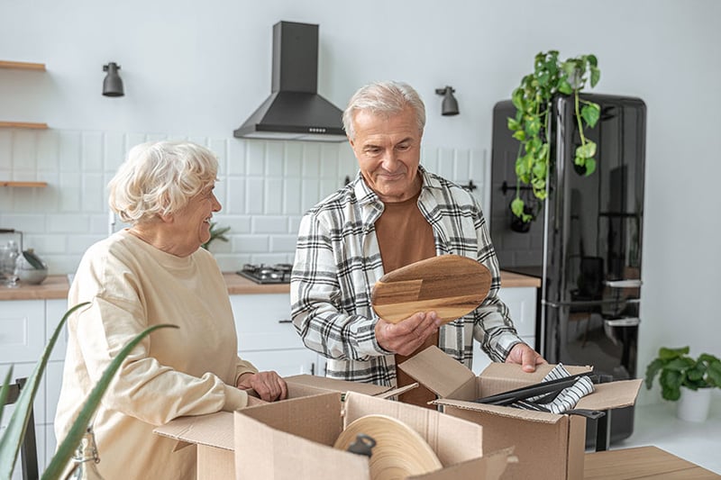 Two residents unboxing items in a facility kitchen