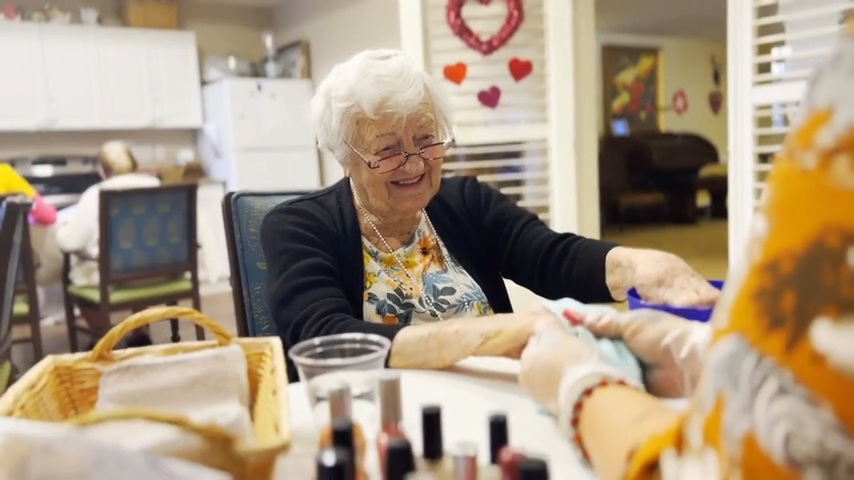 Residents enjoying manicures in a communal activity.