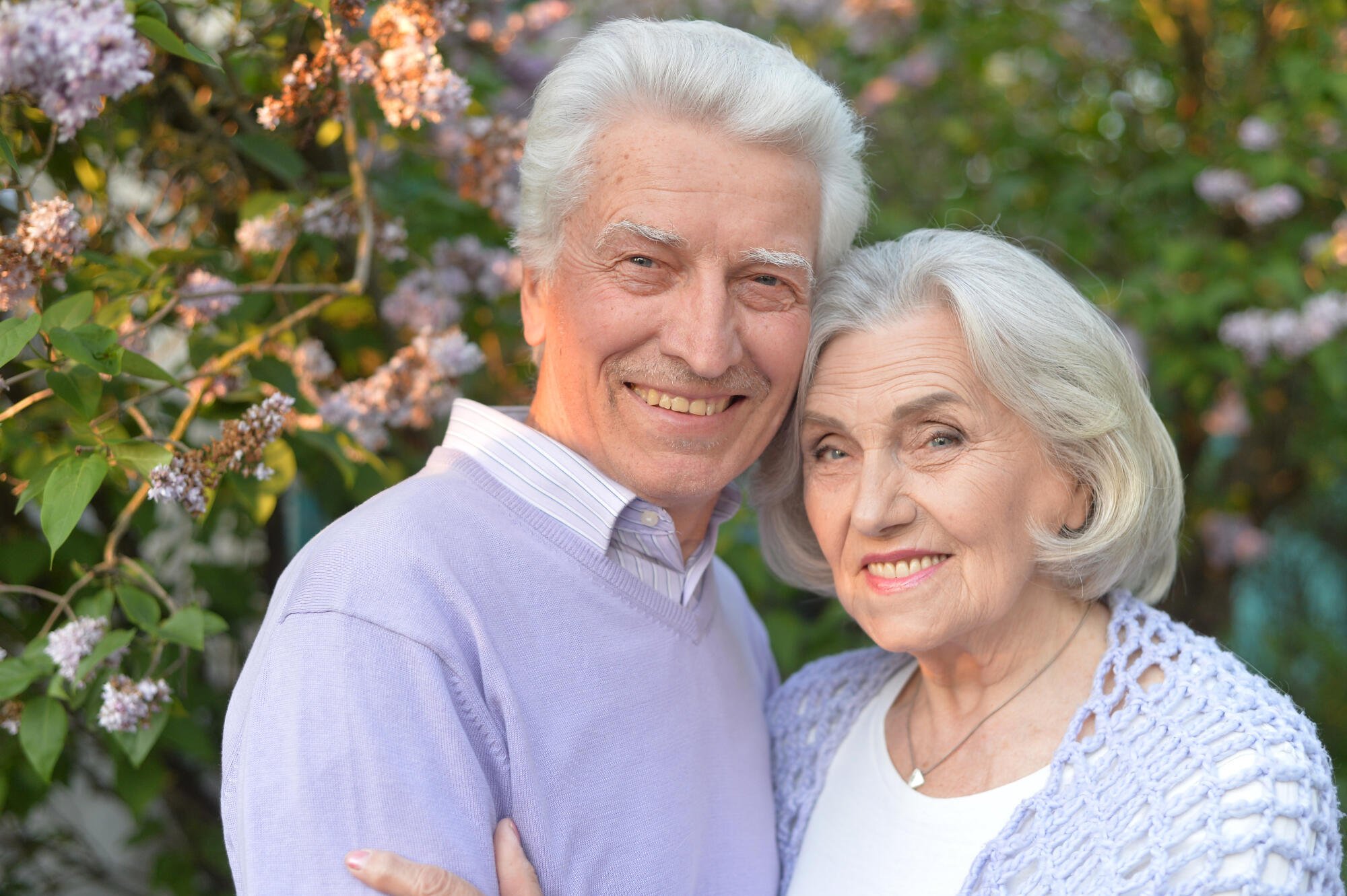 Happy elderly couple posing outdoors with flowers