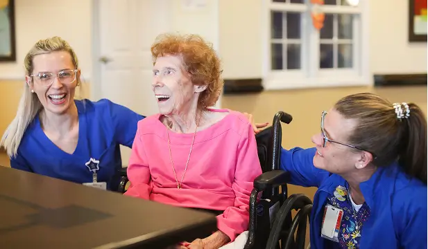 Staff and resident smiling together in a common area