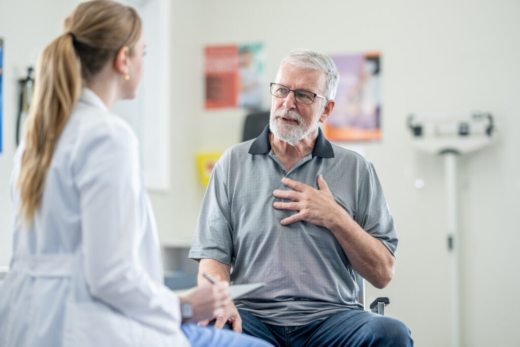 Elderly man conversing with a nurse in a healthcare setting
