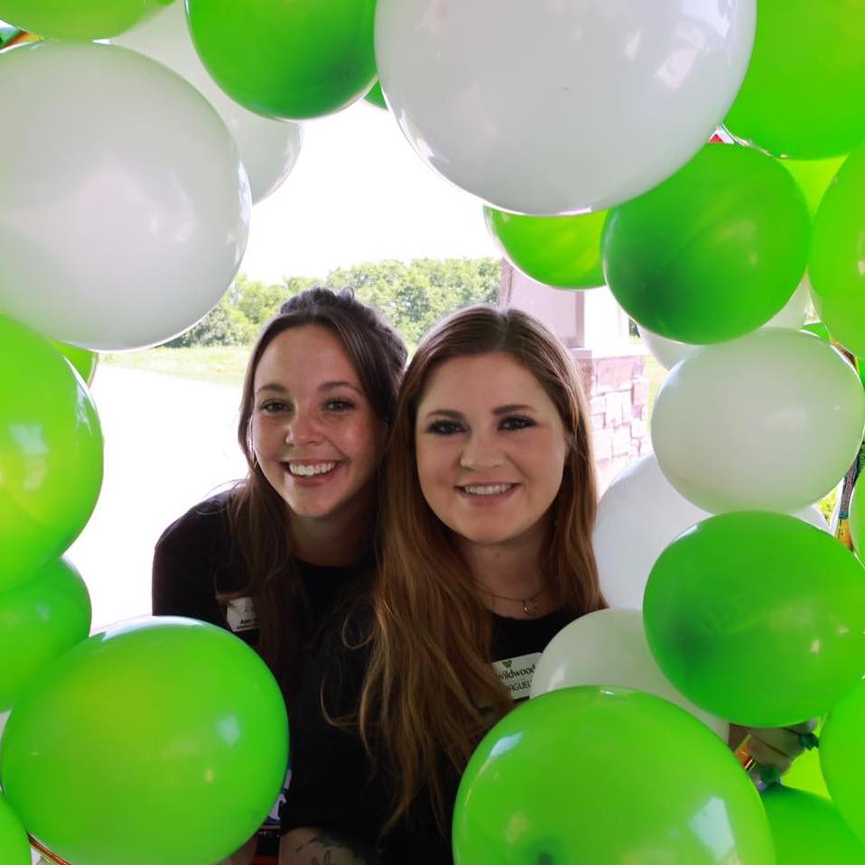 Two staff members smiling amidst balloons