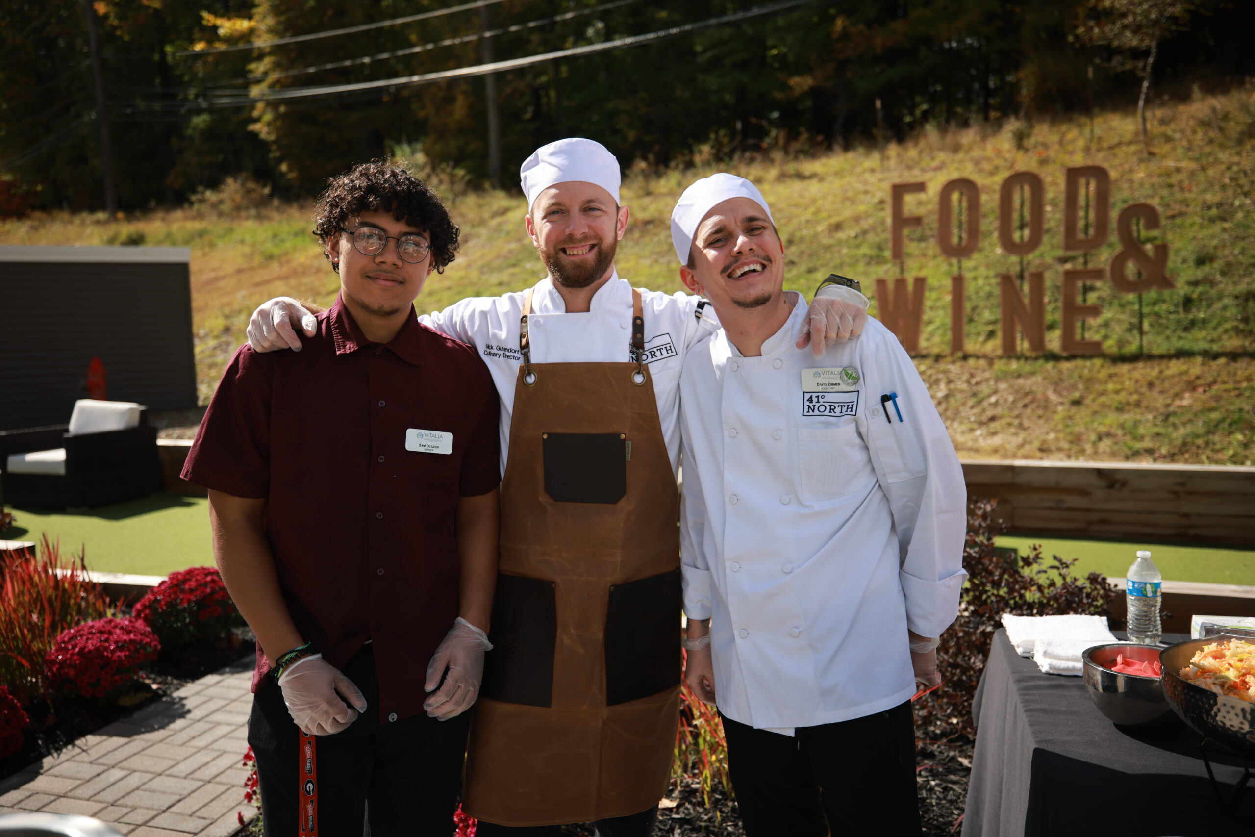 Three staff members smiling outside during a food event